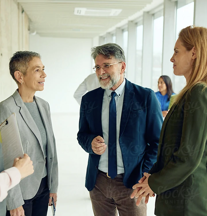 Drei Kolleginnen und Kollegen im Gespräch auf einem Bürokorridor